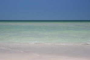 A beach with clear turquoise water and a sandy shore. - Three Bedroom Beachfront | Top Floor | Panoramic Gulf Views | Heated Pool, Tiki Bar & Beach Access (Treasure Island)