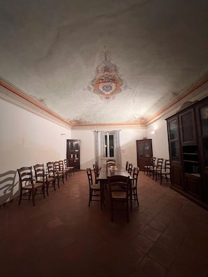 A dining room with a long table and chairs, a decorative ceiling, and wooden cabinets. - Badia del Borgo: A Home in the Millennium-Old Abbey (Toscana)