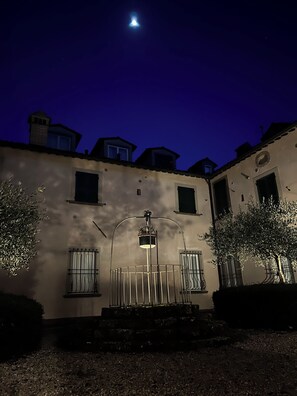 A building with a balcony, a street lamp, and a moon in the sky. - Badia del Borgo: A Home in the Millennium-Old Abbey (Toscana)