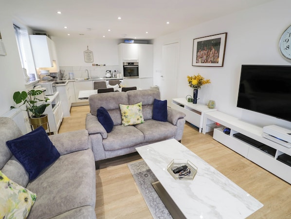 A modern living room with a grey sofa set, a coffee table, and a flat-screen TV.