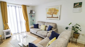 A living room with a sofa set, a coffee table, a radiator, and a potted plant.