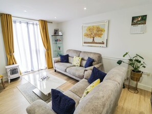 A living room with a sofa set, a coffee table, a radiator, and a potted plant.