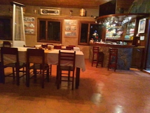 A restaurant with a bar area, wooden chairs, and a tiled floor.