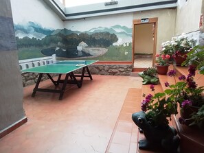 A ping pong table in a room with a mural of mountains and a door labeled 'BATHROOM'. - Hosteria Guagrahuma (Sayausí)