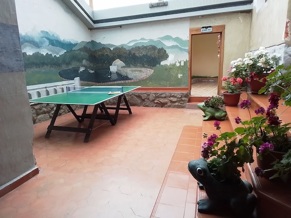 A ping pong table in a room with a mural of mountains and a door labeled 'BATHROOM'.