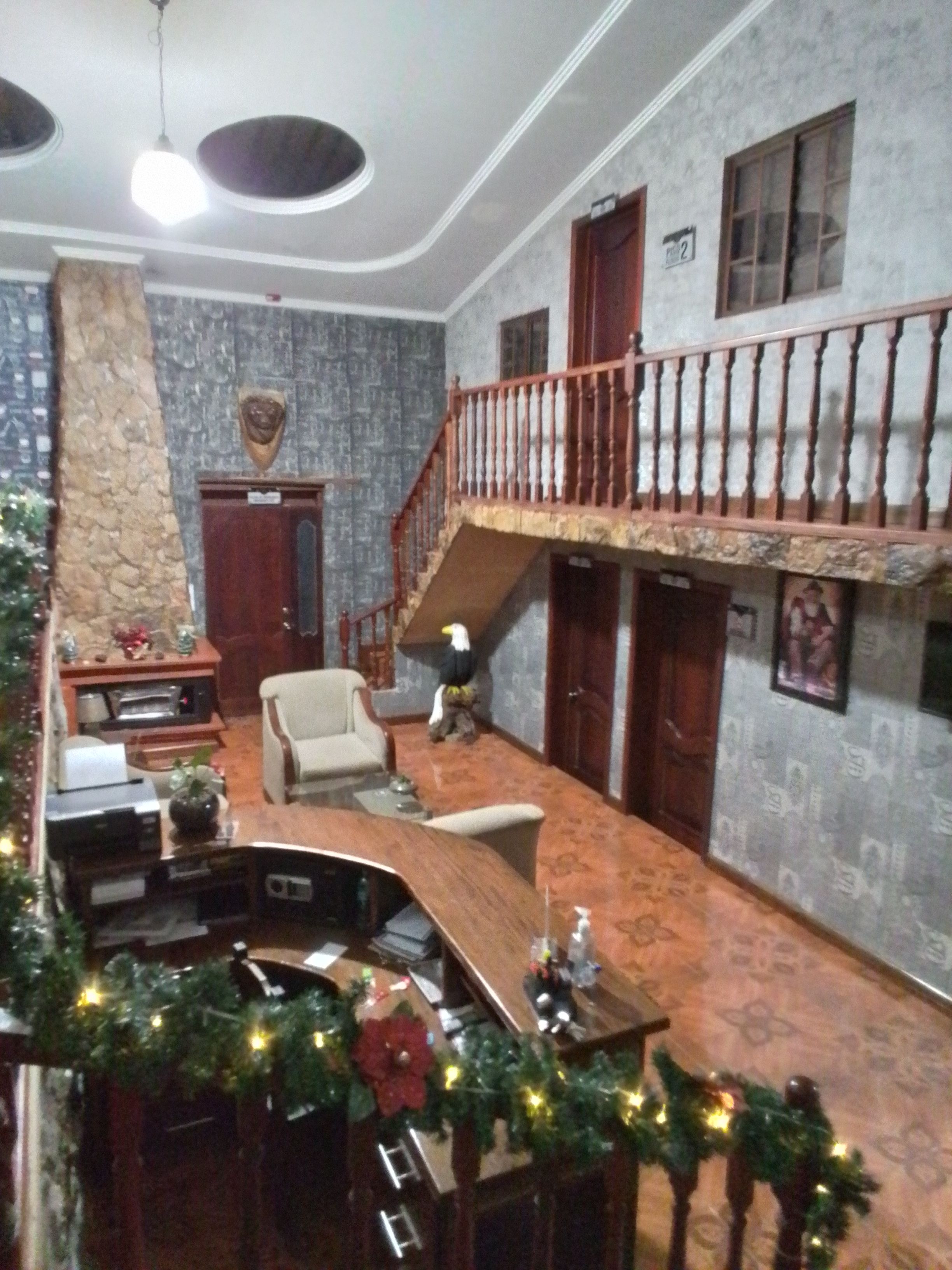 A spacious living area with a high ceiling, a staircase leading to an upper floor, and a fireplace.