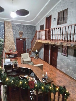 A spacious living area with a high ceiling, a staircase leading to an upper floor, and a fireplace.