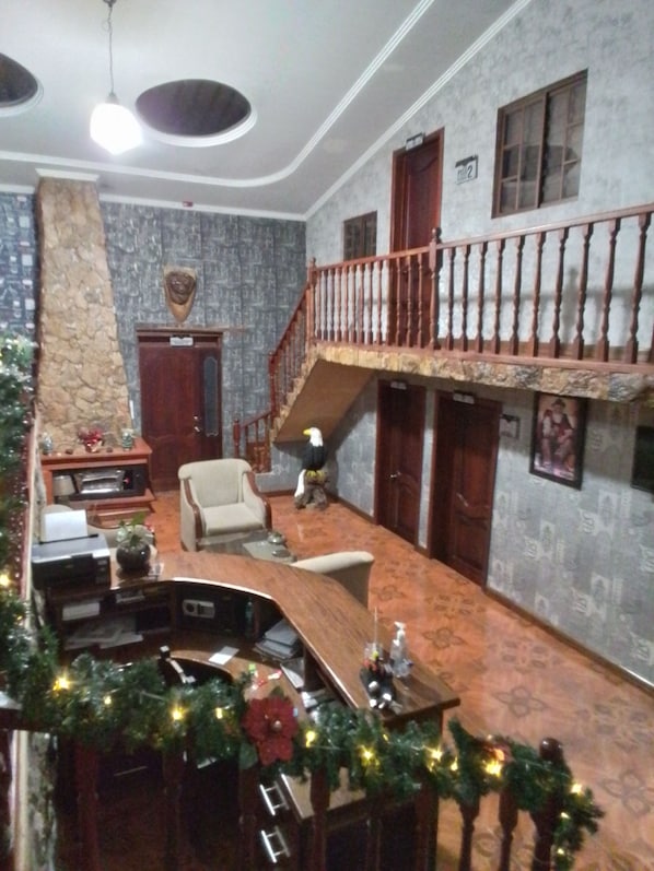 A spacious living area with a high ceiling, a staircase leading to an upper floor, and a fireplace. - Hosteria Guagrahuma (Sayausí)