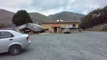 Un bâtiment avec une enseigne indiquant un restaurant, une voiture garée et des montagnes en arrière-plan.