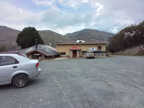 A building with a sign for a restaurant, a parked car, and mountains in the background.