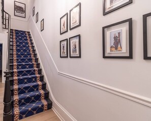 A staircase with a patterned carpet and a handrail, leading to a landing with framed pictures on the wall. - Spruce Villa - 3rd Floor King Studio (Philadelphia)