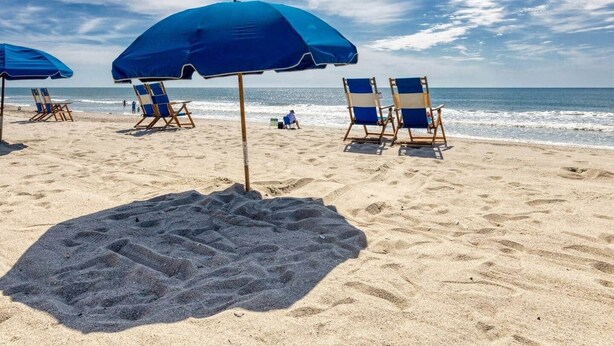 Een strand met blauwe parasols en ligbedden.