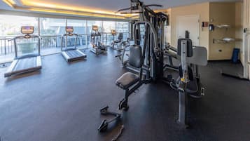 A gym with cardio equipment, weight machines, and a bench.