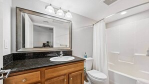 Een badkamer met een wastafel, spiegel, toilet en douche.