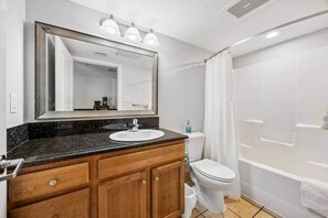 Een badkamer met een wastafel, spiegel, toilet en douche.