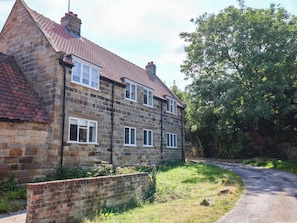 A two-story stone house with a red-tiled roof, a brick wall, and a paved driveway. - EWE COTE HALL FARMHOUSE, pet friendly, with open fire in Whitby (Whitby)
