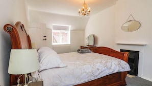 Un dormitorio con cama de madera, una lámpara de noche, un espejo y una chimenea.