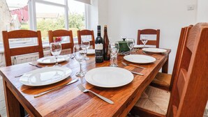Una mesa de comedor servida con platos, cubiertos y copas de vino, con una botella de vino Malbec.