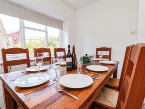 A dining table set with plates, cutlery, and wine glasses, with a bottle of Malbec wine. - EWE COTE HALL FARMHOUSE, pet friendly, with open fire in Whitby (Whitby)