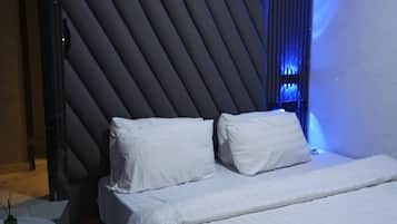 A modern hotel room with a bed, bedside tables, an air conditioning unit, and a unique wall design.