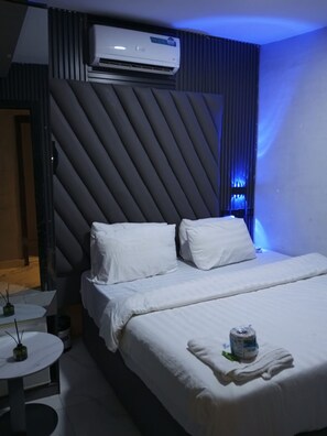 Een moderne hotelkamer met een bed, nachtkastjes, een airconditioner en een uniek wandontwerp.