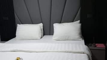 A hotel room with a large bed, a headboard, and a bedside table with a lamp and a phone.