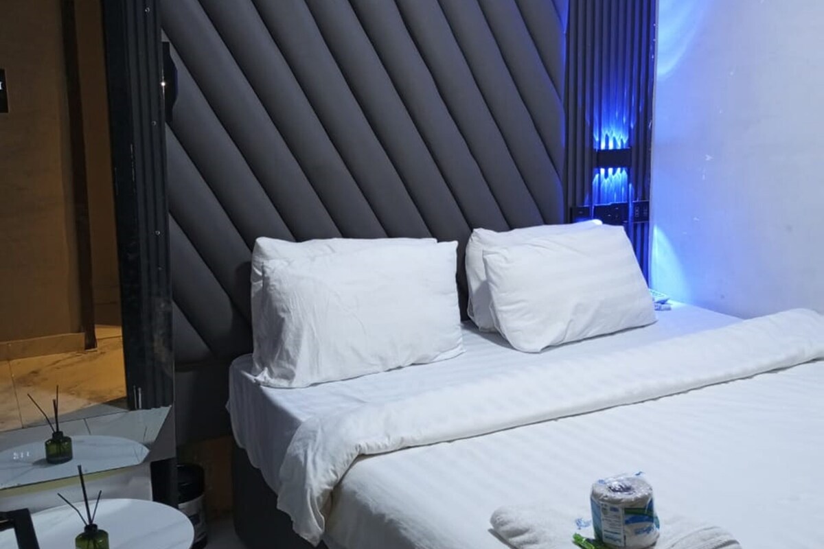 Een hotelkamer met een bed, een klein tafeltje en een airconditioning.