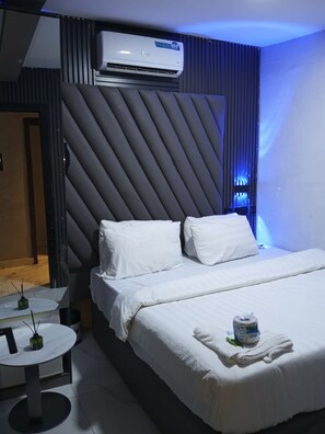Een hotelkamer met een bed, een klein tafeltje en een airconditioning.