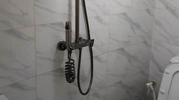 A bathroom with a shower, toilet, and a marble-tiled wall.