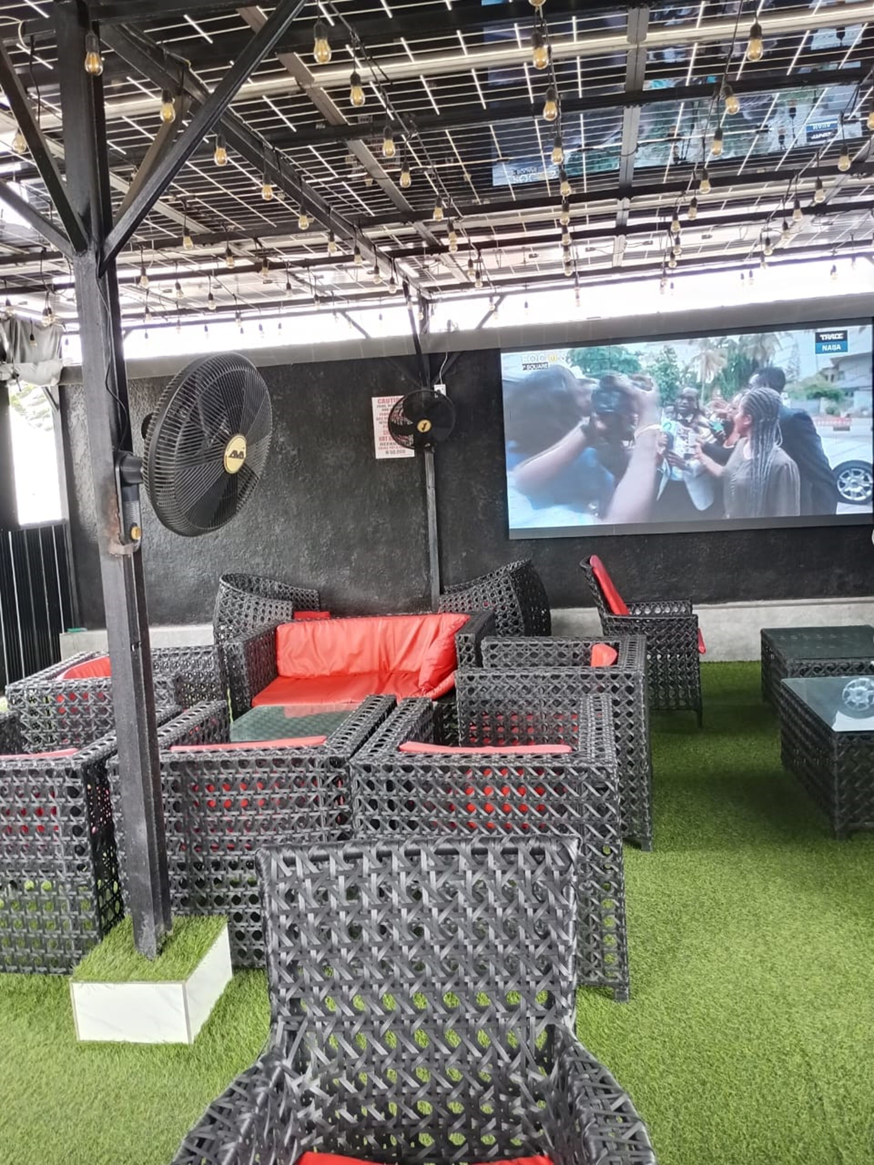 Un área de descanso con mobiliario de mimbre y una pantalla grande para ver.