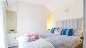 A bedroom with a bed, pillows, a bedside table, a lamp, and a wall-mounted shelf with a plant. - HARBOUR COTTAGE, pet friendly, country holiday cottage in Barmouth (Barmouth)