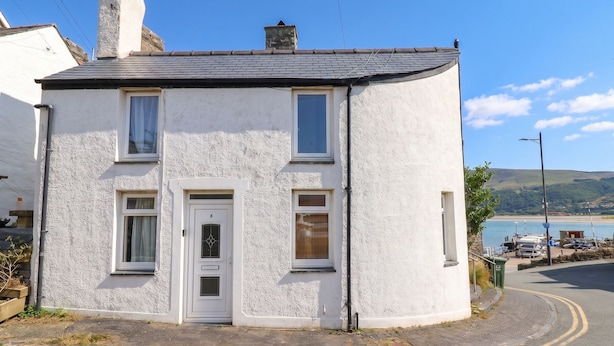 A two-story white house with a grey roof, a white door, and two windows on the ground floor. - HARBOUR COTTAGE, pet friendly, country holiday cottage in Barmouth (Barmouth)