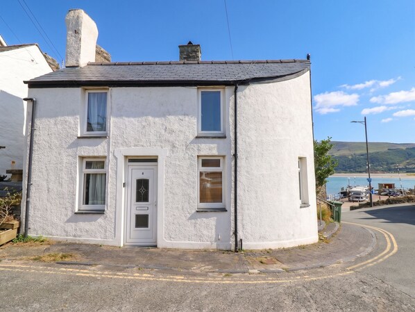 A two-story white house with a grey roof, a white door, and two windows on the ground floor. - HARBOUR COTTAGE, pet friendly, country holiday cottage in Barmouth (Barmouth)
