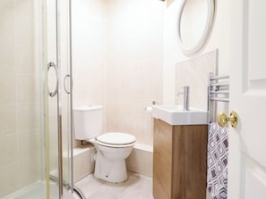 A bathroom with a toilet, a sink, a mirror, and a shower enclosure. - HARBOUR COTTAGE, pet friendly, country holiday cottage in Barmouth (Barmouth)
