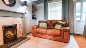 Ein Wohnzimmer mit Kamin, einer Ledersofa und einem Spiegel an der Wand.