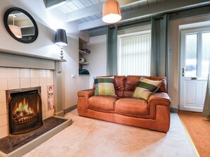 Un salon avec une cheminée, un canapé en cuir et un miroir au mur.