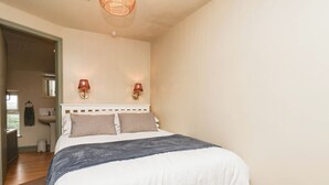 Ein Schlafzimmer mit einem Bett, zwei Wandleuchten, einer Deckenlampe, einem Fenster und einer Tür zu einem anderen Raum.