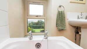 Ein Badezimmer mit einer Badewanne, einem Fenster und einem Waschbecken.