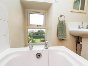 Une salle de bain avec une baignoire, une fenêtre et un lavabo.