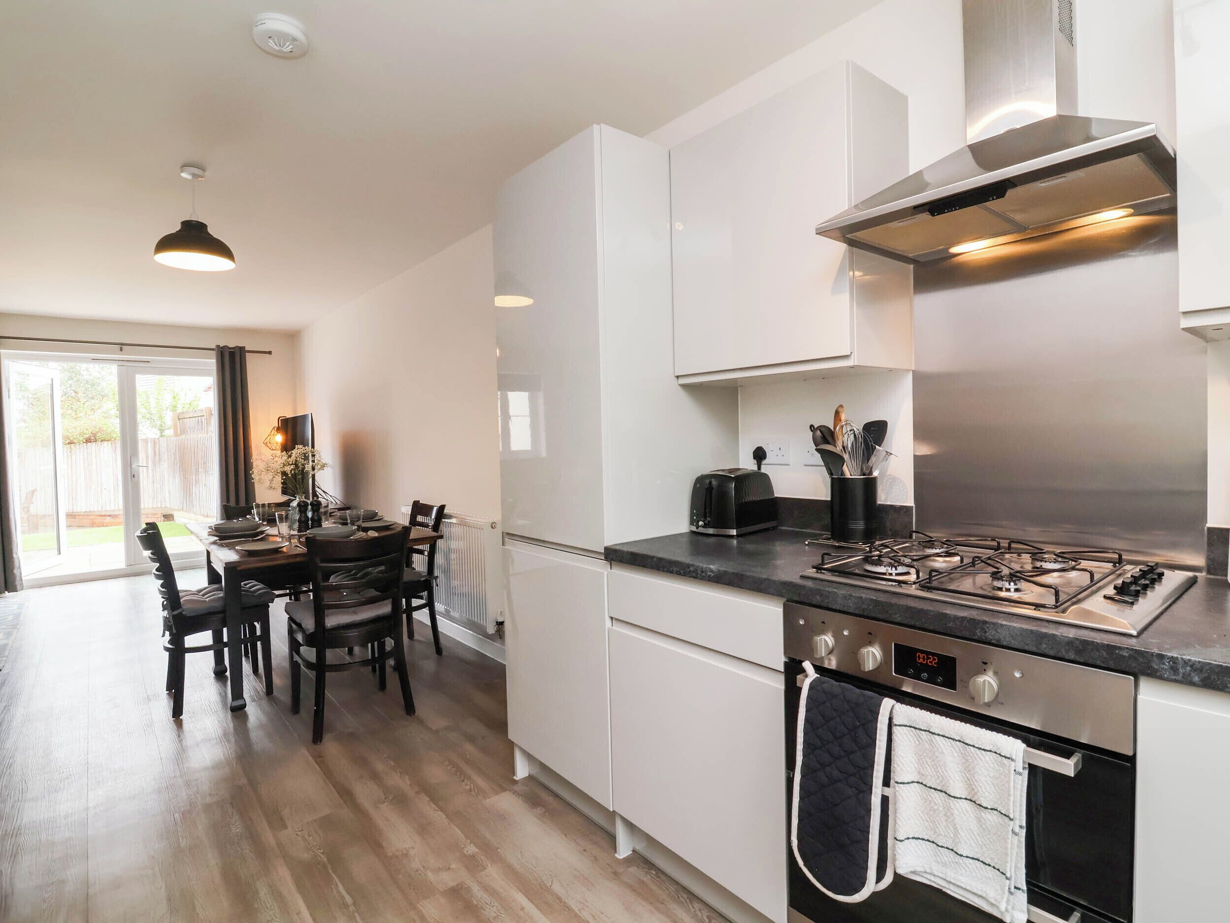 Eine moderne Küche mit Gaskochfeld, Backofen und Essbereich mit Tisch und Stühlen.