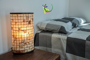 Een kamer met een traditionele Japanse kachel, een bed met beddengoed met een patroon en een muur met een kleurrijk logo.