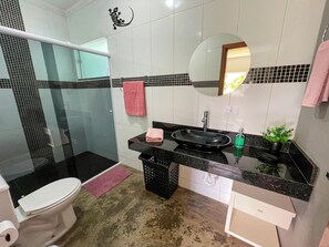 Een badkamer met toilet, wastafel, spiegel en douche.