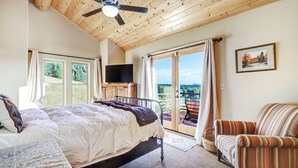 A bedroom with a bed, a chair, a television, and a balcony with a view. - Cascade Overlook in Angel Fire (Angel Fire)