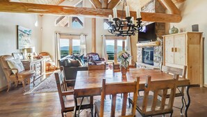 A spacious living room with a wooden dining table, leather furniture, and a stone fireplace. - Cascade Overlook in Angel Fire (Angel Fire)