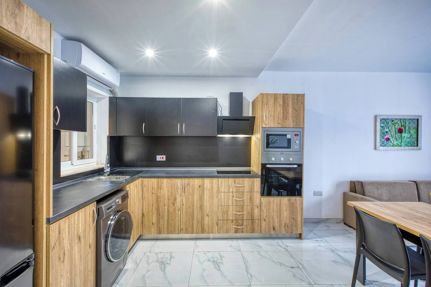 Cocina compacta con horno integrado, microondas y lavadora.
