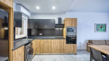 Cocina compacta con horno integrado, microondas y lavadora.