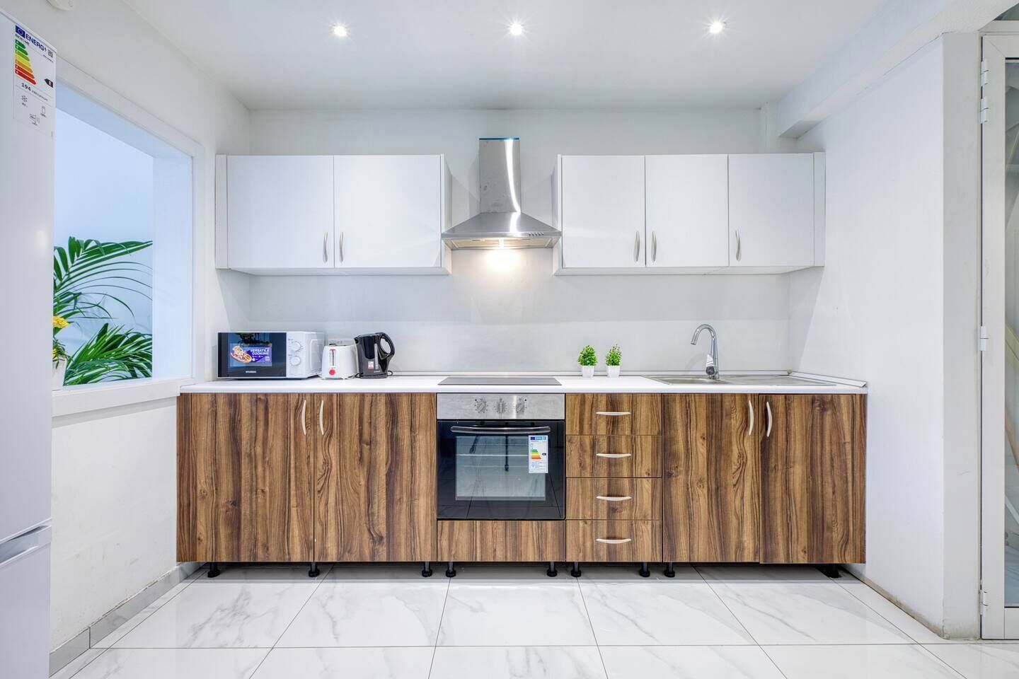 A modern kitchen with white cabinets, a built-in oven, and a wooden countertop.