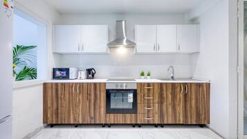 A modern kitchen with white cabinets, a built-in oven, and a wooden countertop.