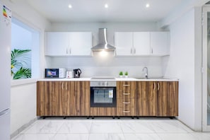 Une cuisine moderne avec des meubles blancs, un four encastré et un plan de travail en bois.