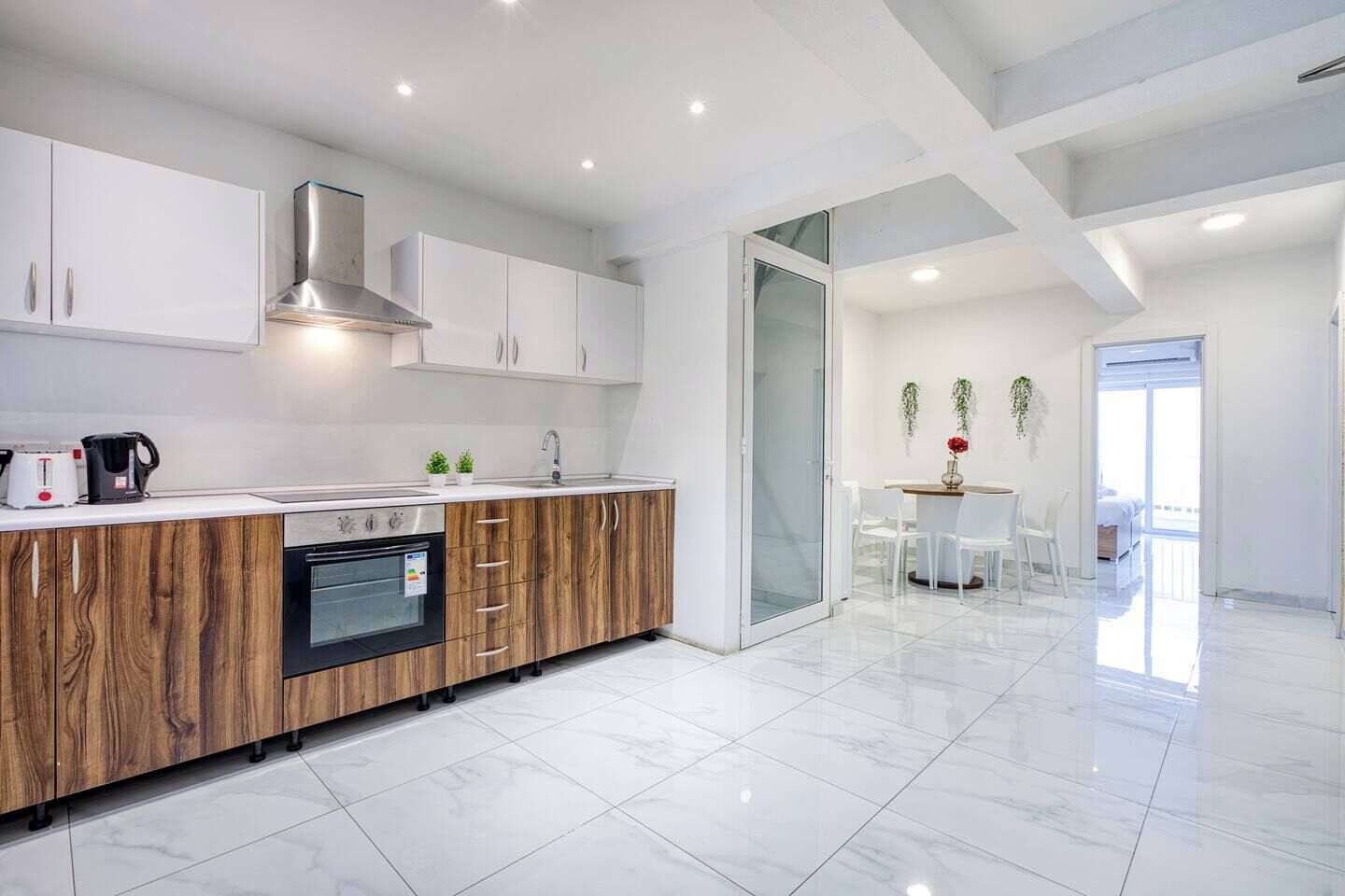A modern kitchen with a built-in oven, a stainless steel range hood, and a white countertop.